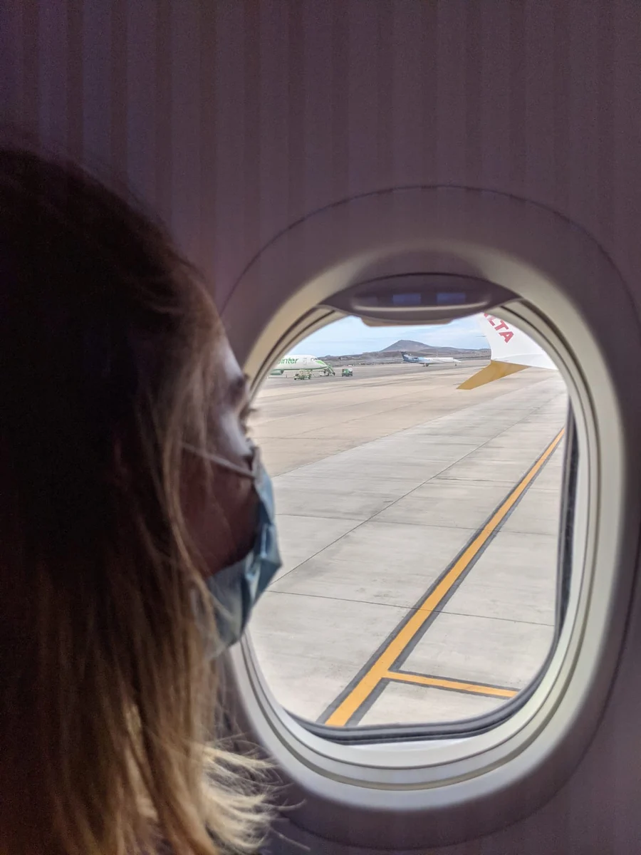 Mujer con mascarilla mira por la ventanilla del avión la pista del aeropuerto de Gran Canaria al llegar