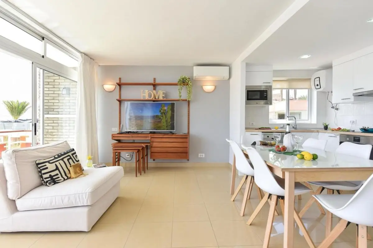 Salón-comedor luminoso y amueblado de un alojamiento de coliving con cocina abierta