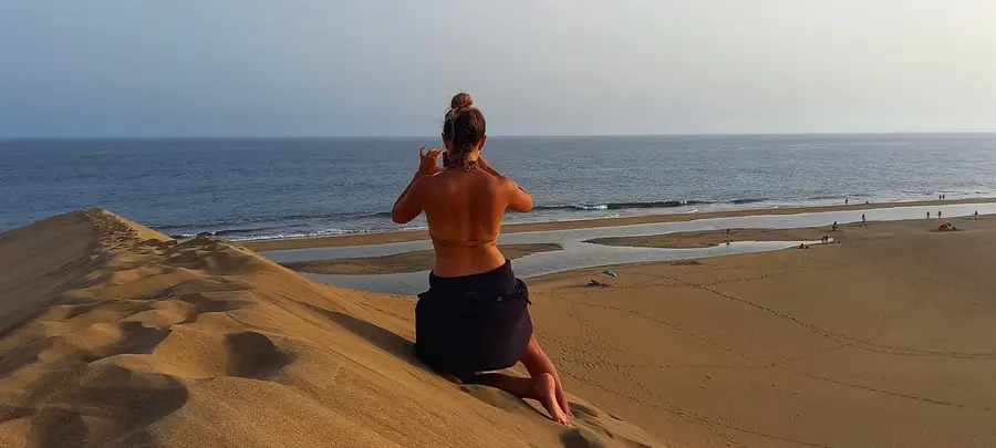 Persona contemplando el mar al atardecer desde las dunas de Maspalomas