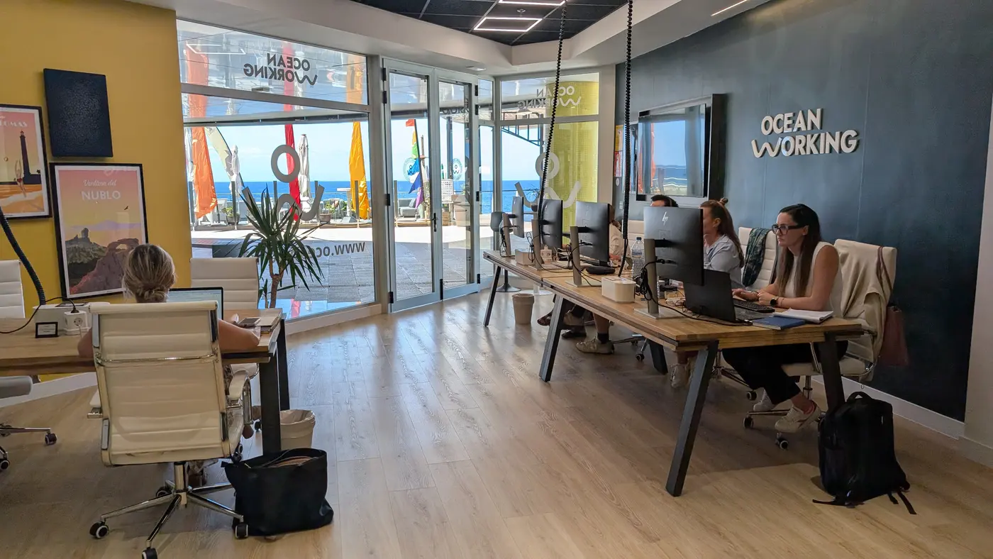 Profesionales trabajando en los puestos del coworking OceanWorking con el mar al fondo