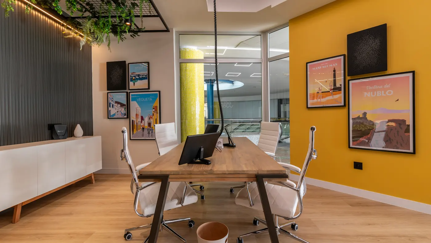 Puesto compacto en el coworking Oceanworking con monitor y carteles ilustrados de Canarias