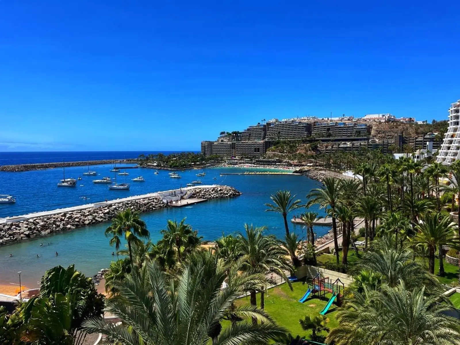 Bahía de Anfi del Mar con aguas turquesas, barcos, palmeras y resorts en la costa de Gran Canaria