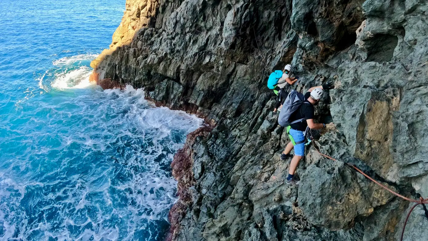 Dos personas recorren una vía ferrata en un acantilado sobre el mar en Gran Canaria