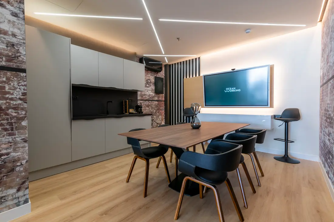 Sala de reuniones del coworking OceanWorking con mesa de madera y pantalla