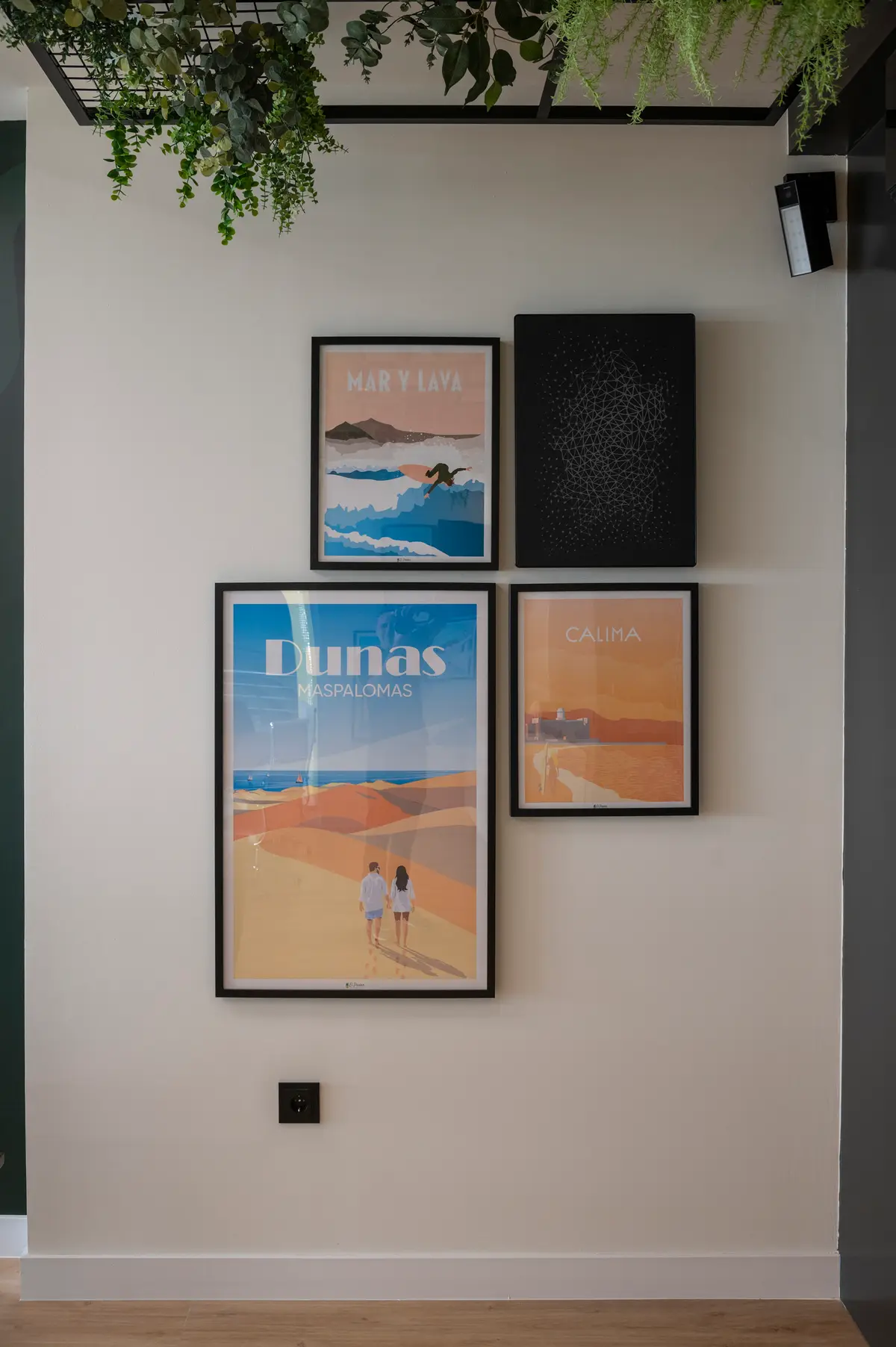 Detalle decorativo del coworking con láminas ilustradas de Canarias y plantas colgantes