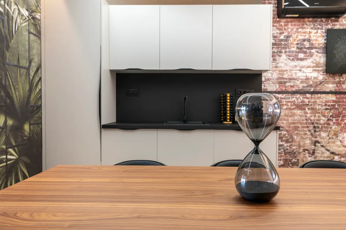 Office del coworking con encimera, pared de ladrillo y un reloj de arena sobre la mesa de madera