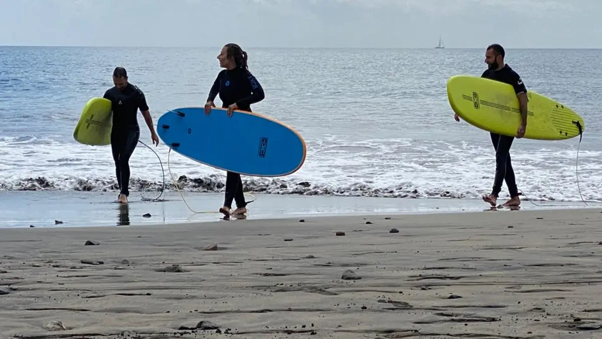 Tres personas en neopreno caminan por la playa con sus tablas de surf en Gran Canaria