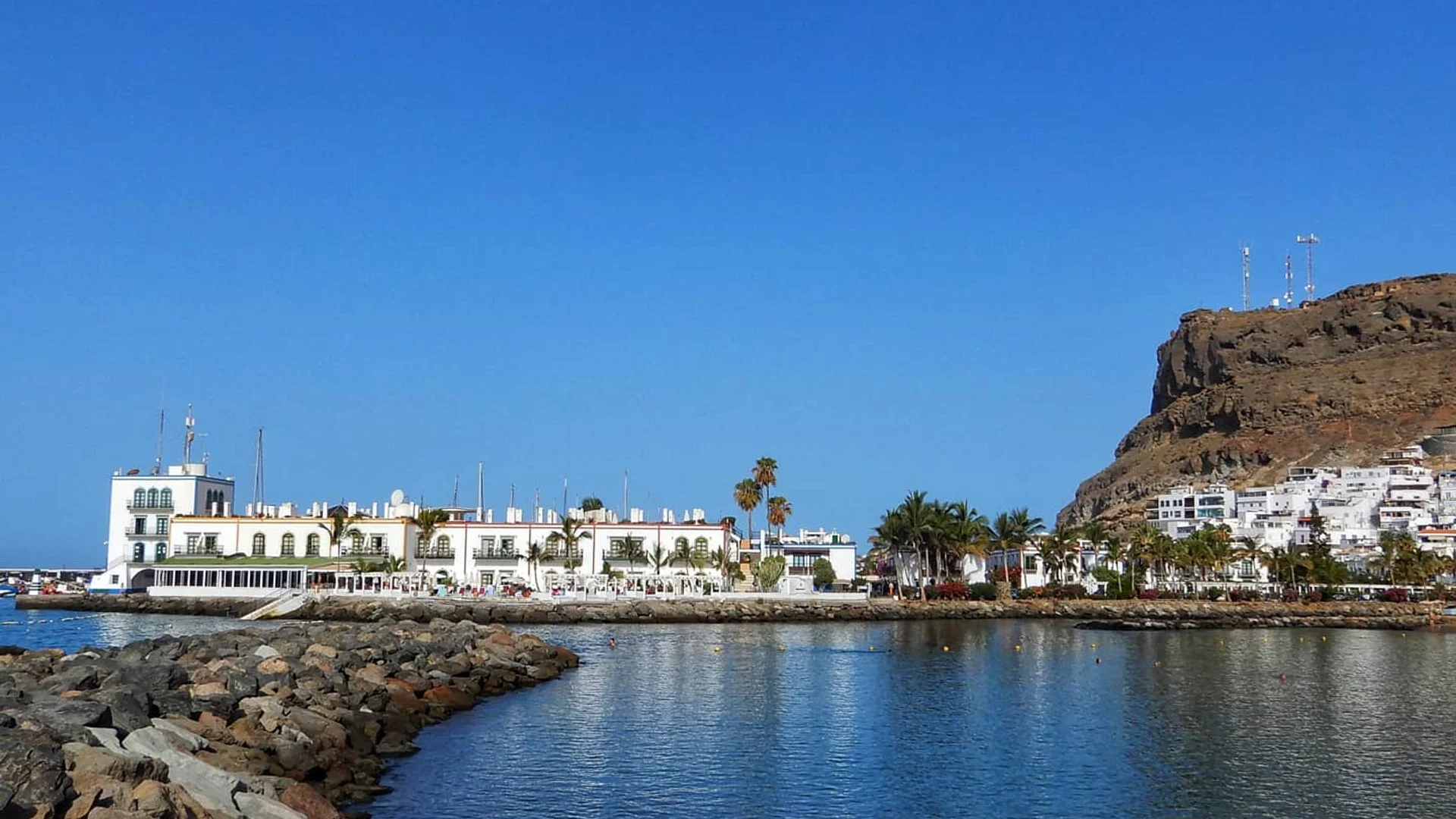 Puerto deportivo de Puerto de Mogán en Gran Canaria, con edificios blancos, palmeras y montaña al fondo