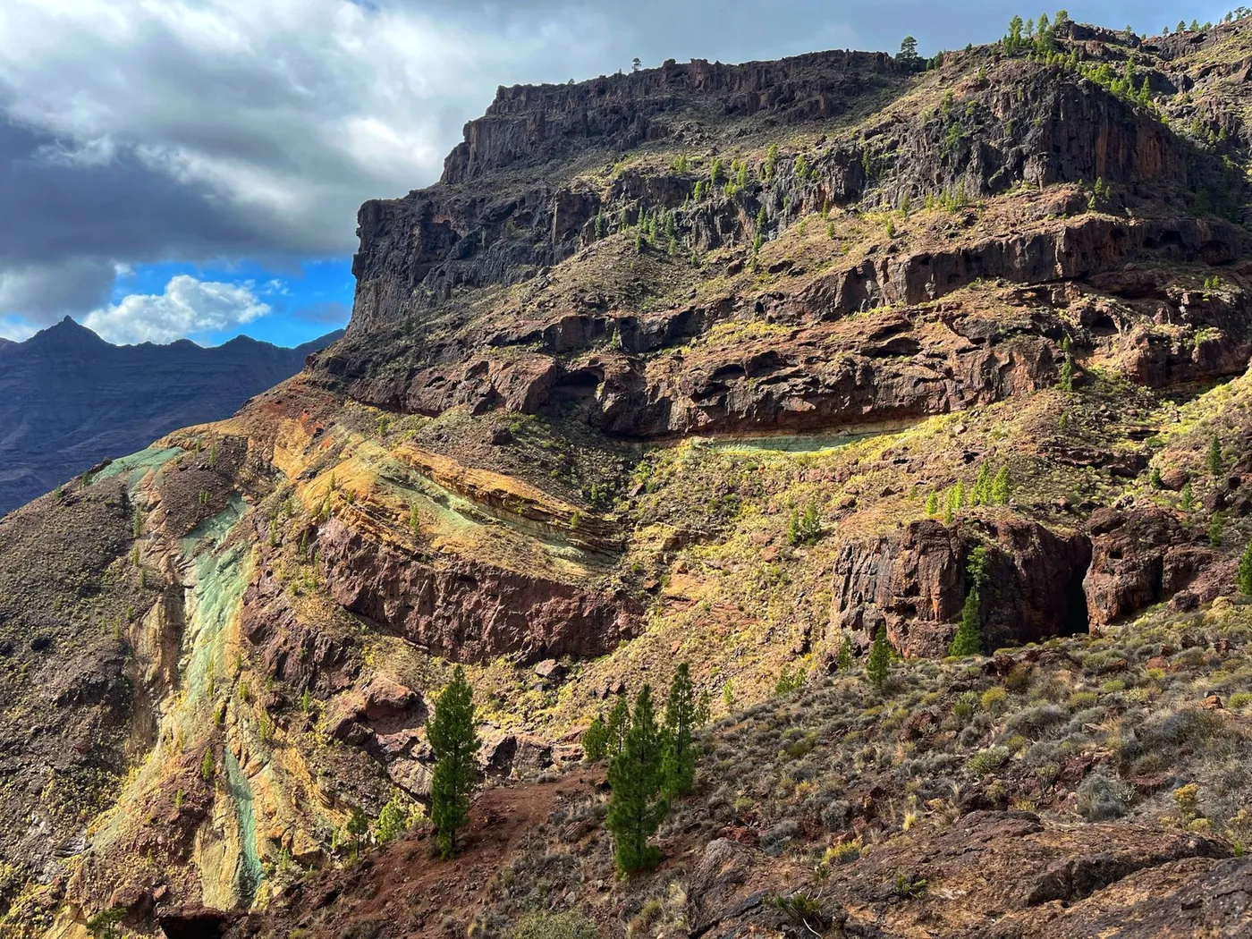 Rock wall with green, yellow and reddish veins beside the GC-200 road on Gran Canaria.