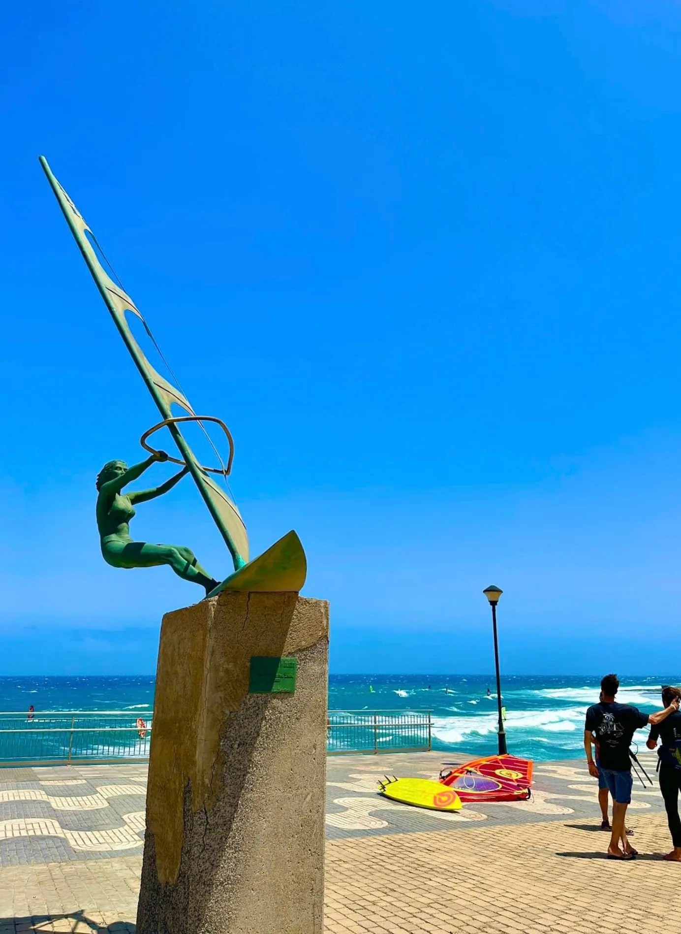 Windsurfista deslizándose sobre el mar agitado de Pozo Izquierdo, con la vela tensada por el viento constante del sureste de Gran Canaria.