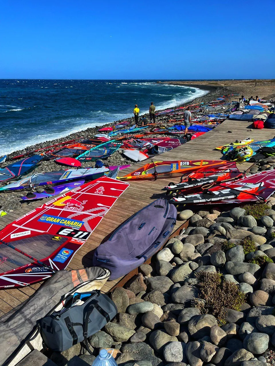 Varias velas de windsurf de colores recortadas contra el oleaje y el cielo de la costa sureste de Gran Canaria.
