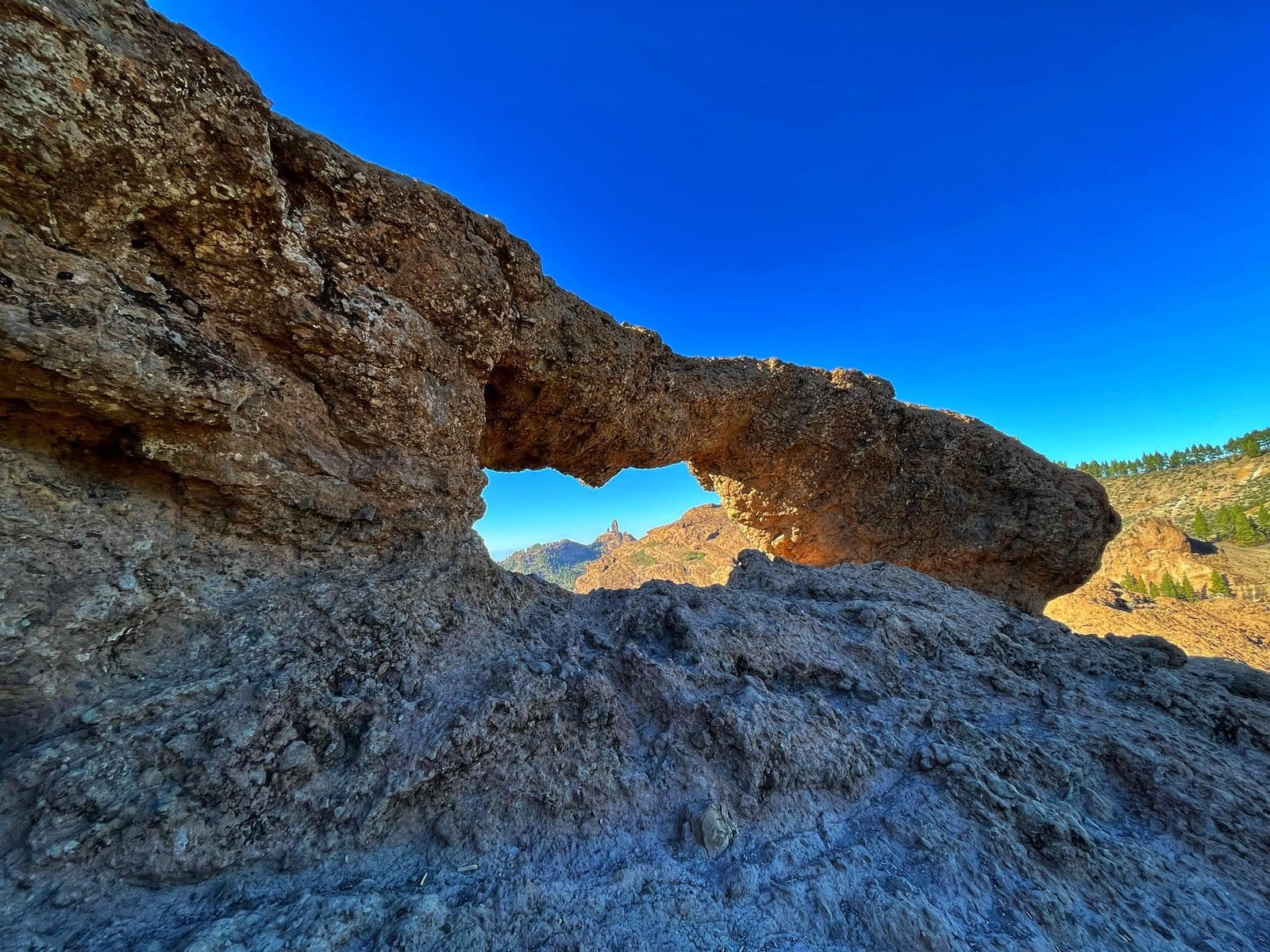 Ein natürliches Fenster aus Vulkangestein rahmt den Roque Nublo im bergigen Herzen Gran Canarias